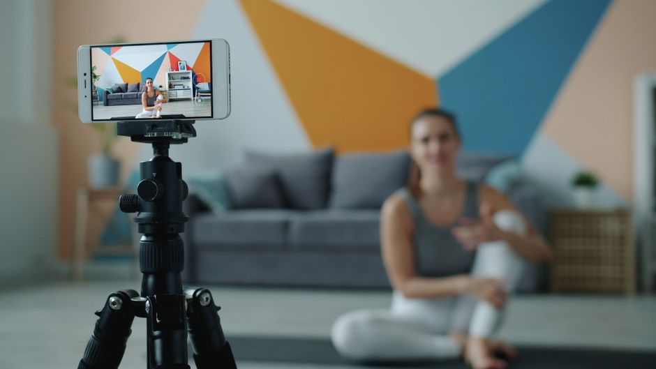 fitness trainer filming workout video with smartphone tripod